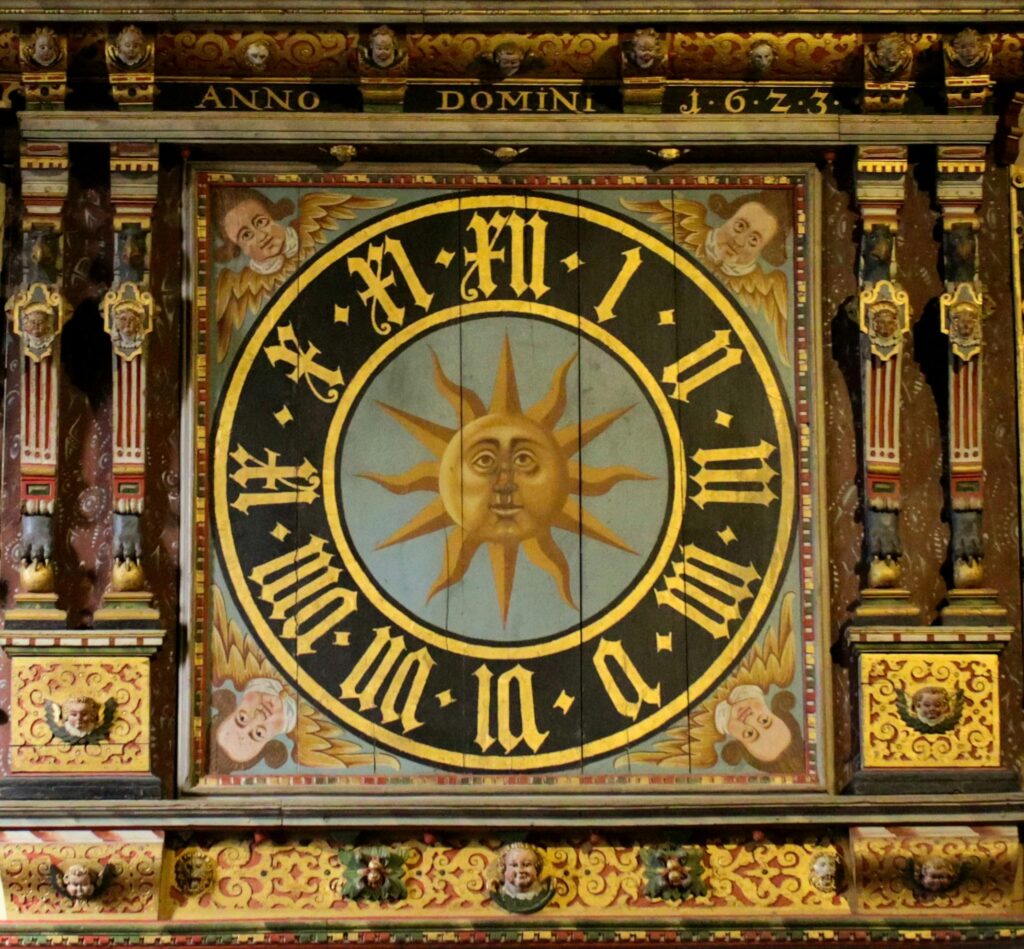 An ornate astronomical clock featuring a sun motif located in Lund Cathedral, Sweden.